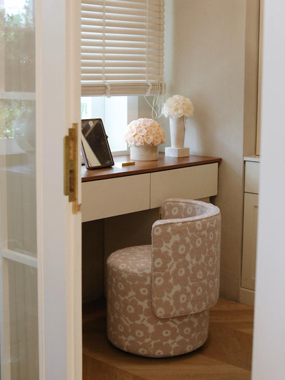 
A window-side desk paired with a patterned chair. On the desk, there are two floral arrangements, including a pot of beige eternal roses, bringing a touch of nature and elegance to the space.