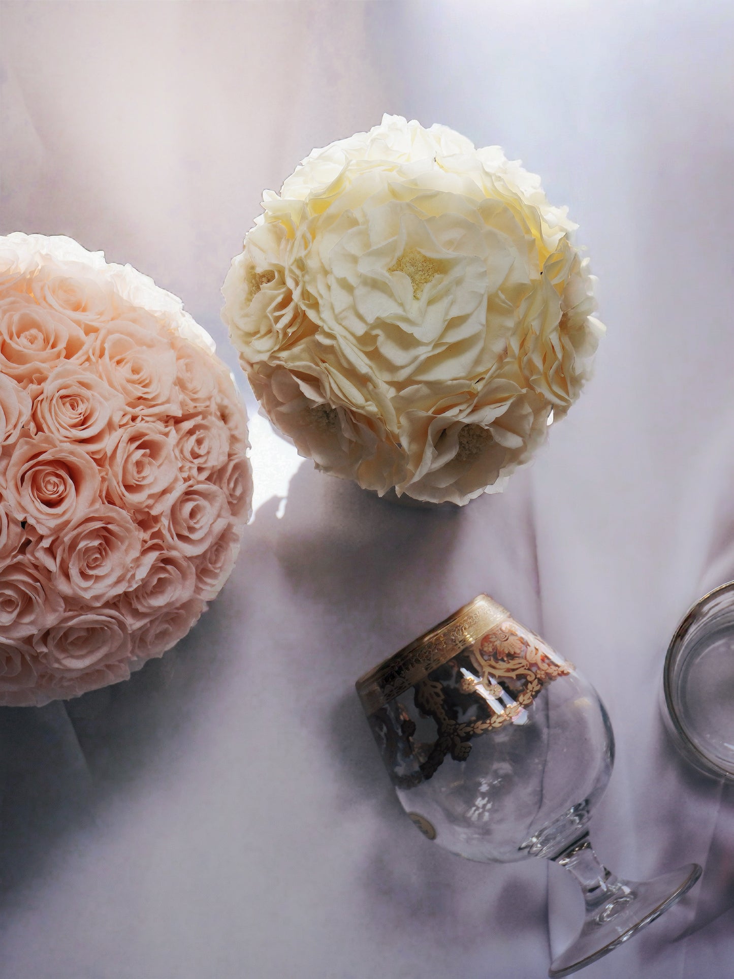 A bouquet of preserved flowers in a travertine vase is placed next to a bottle of wine and elegant glasses, creating a warm and refined home decor scene.