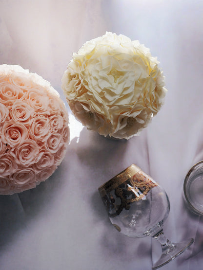 A bouquet of preserved flowers in a travertine vase is placed next to a bottle of wine and elegant glasses, creating a warm and refined home decor scene.